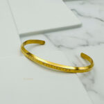 نمای نزدیک از سطح صیقلی و رنگ طلایی دستبند Daniel Wellington مدل ELM8242